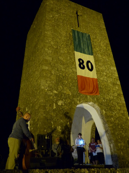 Italienische Flagge mit großer Zahl "80§ am Turm des Ossario , dem Mahnmal für die Opfer des Massakers von sSant'Anna di Stazzema