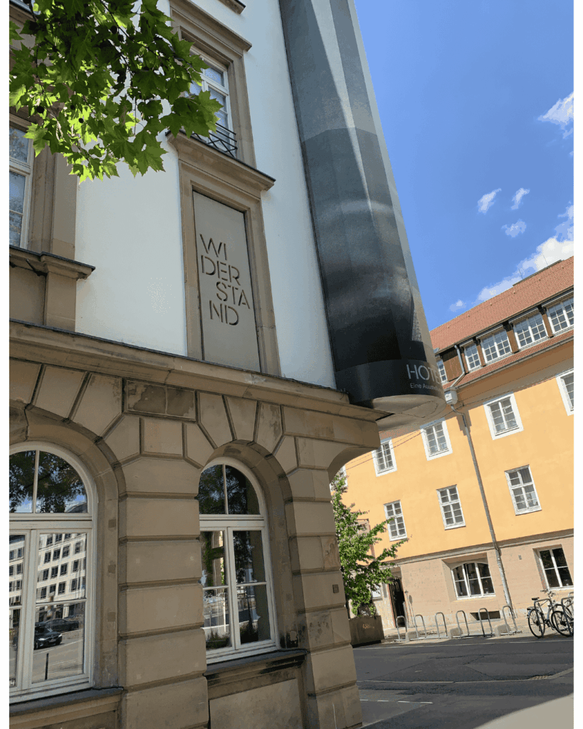 Eingang des Erinnerungsorts Hotel Silber Ausschnitt Fensterverfremdung mit dem Schriftzug"Widerstand".Blick richtung "Altes Waisenhaus"