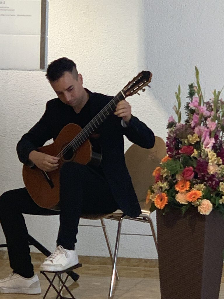 Der Gitarrist Jonas Khalil bsitzend beim Gitarre spielen im Stuttgarter Rathaus